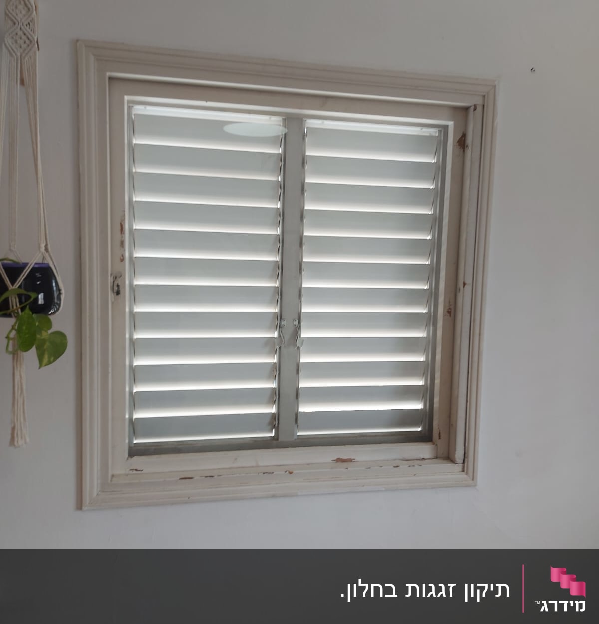 חלון עם תריסים סגורים בתוך מסגרת עץ לבנה